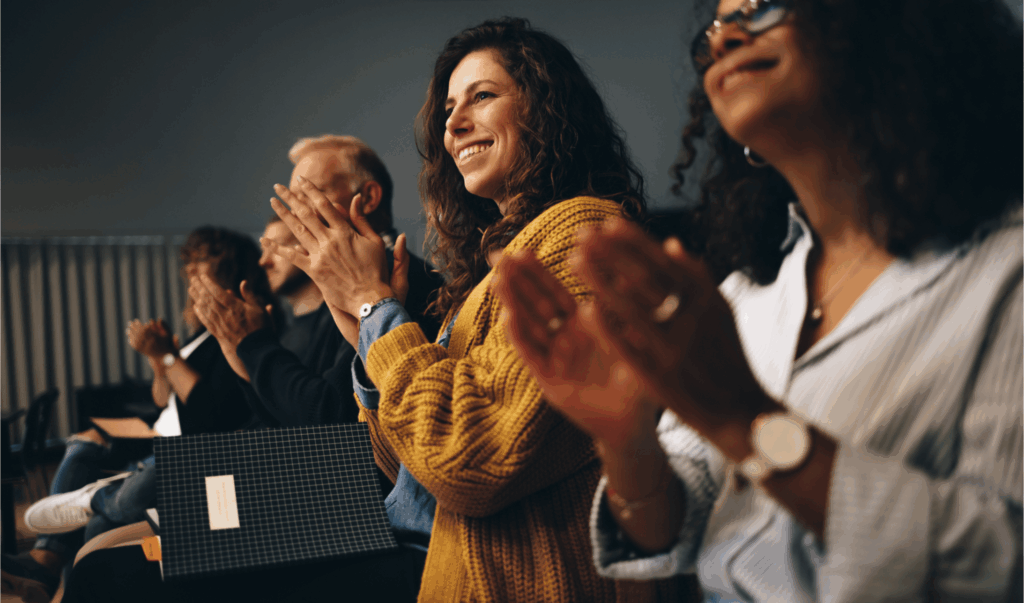 Attendees applauding in a darkened conference auditorium